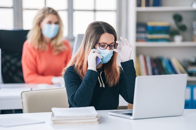 Colleagues in the office working while wearing medical face mask during COVID-19