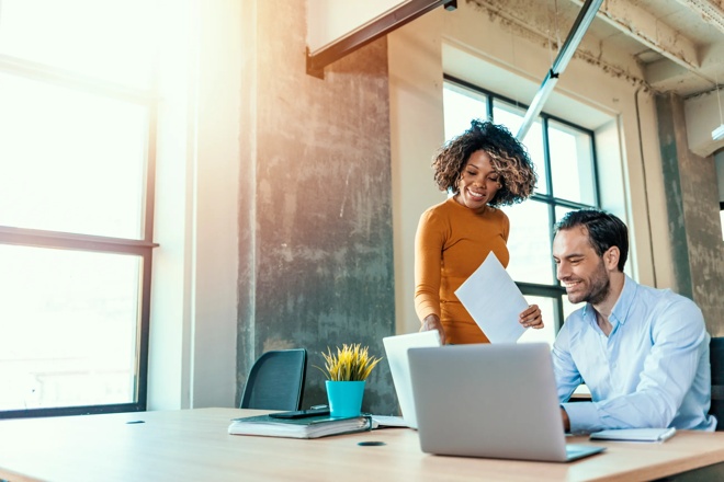 Man and woman looking at laptop and paperwork