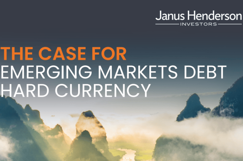Imagen de portada para una publicación de Janus Henderson Investors titulada «Argumentos a favor de la deuda en moneda fuerte de los mercados emergentes». El título se muestra en mayúsculas grandes y destacadas, con «THE CASE FOR» en Orange y «EMERGING MARKETS DEBT HARD CURRENCY» en blanco. El logotipo de Janus Henderson Investors aparece en la esquina superior derecha. El fondo muestra un dramático paisaje montañoso con escarpados picos cubiertos de niebla que se elevan sobre las nubes, iluminados por la suave luz del amanecer o el atardecer. El cielo pasa de azul oscuro en la parte superior a una luz pálida cerca del horizonte, creando una escena tranquila y atmosférica.