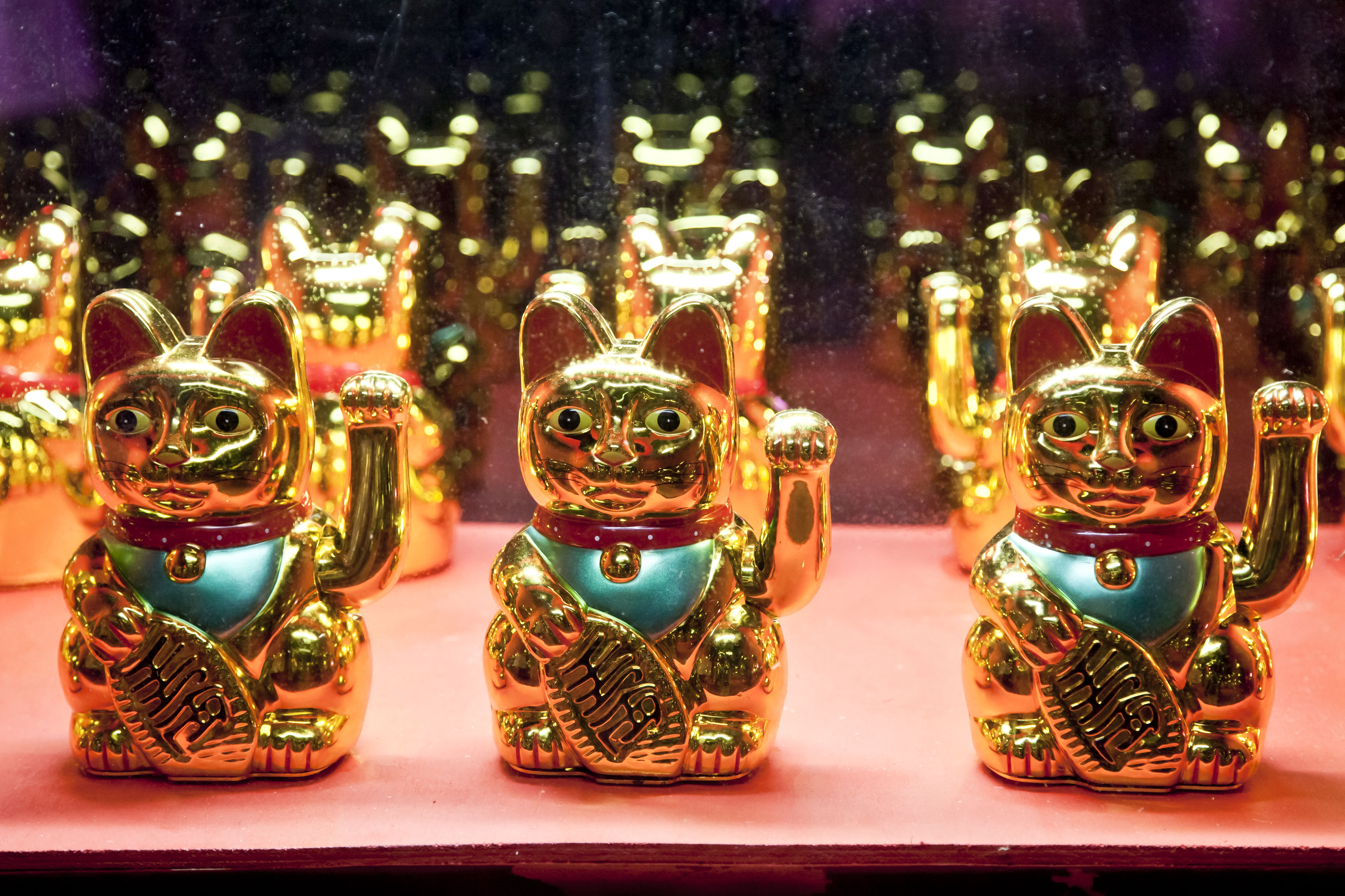Image of several Chinese lucky cat figures on a shelf.