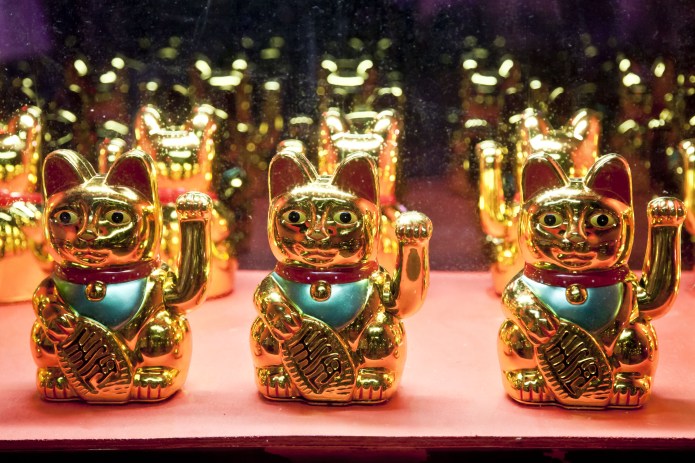 Image of several Chinese lucky cat figures on a shelf.