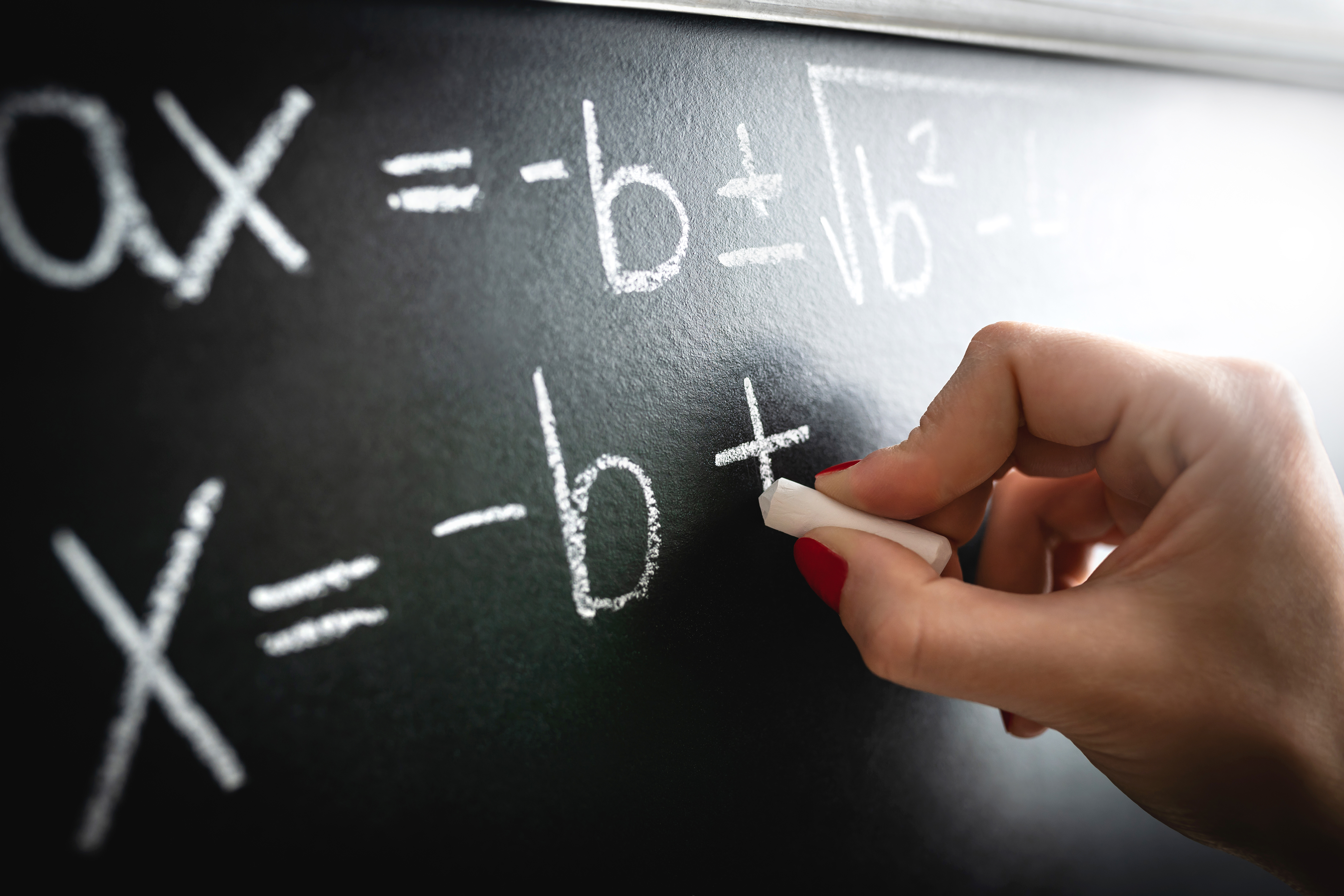 Mathematische Gleichung, Funktion oder Berechnung auf einer Tafel. Lehrer, der bei einem Unterrichtsvortrag an die Tafel in einem Klassenzimmer schreibt. Student oder Tutor beim Rechnen oder Professor bei der Arbeit.