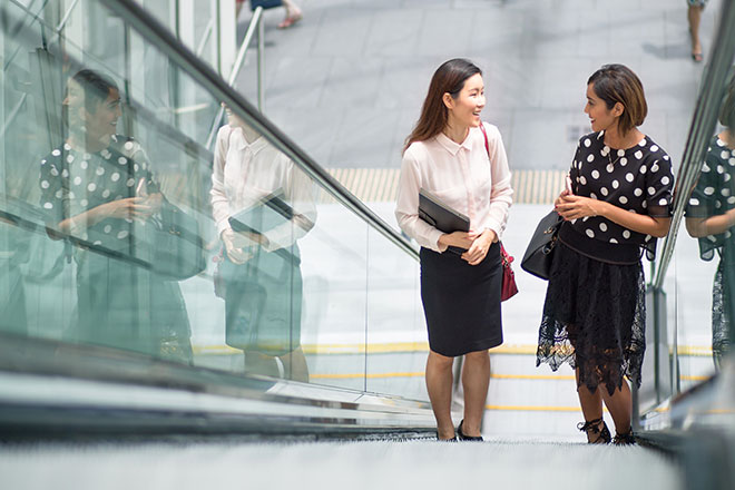 Two women talking on an escalator