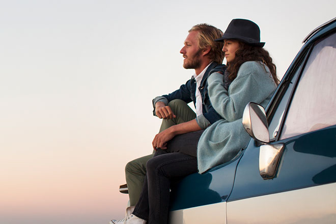 Man and woman sitting on a truck watching the sunset