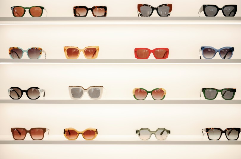 Gafas de sol de colores con diferentes monturas en estanterías.