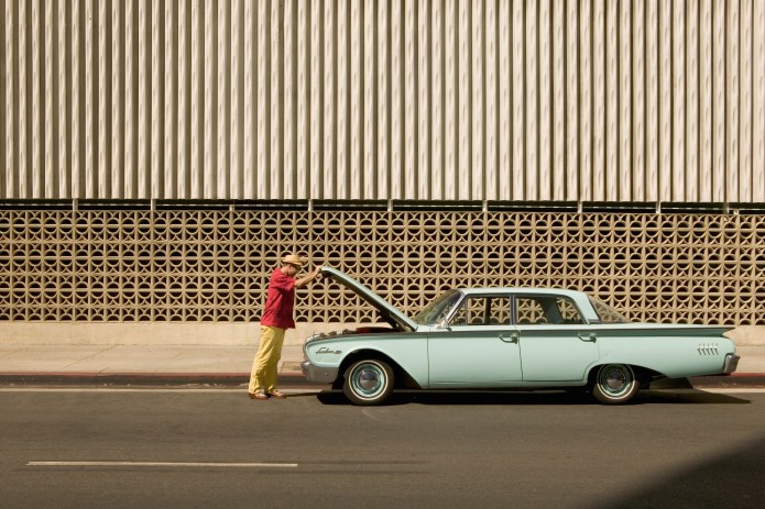 Man looking under the hood of a classic pale green car
