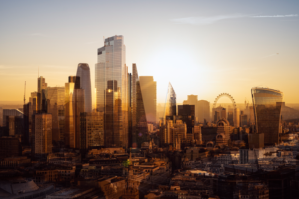 Panoramic view of London’s financial district at sunset, showing the City skyline with modern glass skyscrapers, including the Walkie Talkie and surrounding towers, bathed in warm golden light with the London Eye visible in the distance.