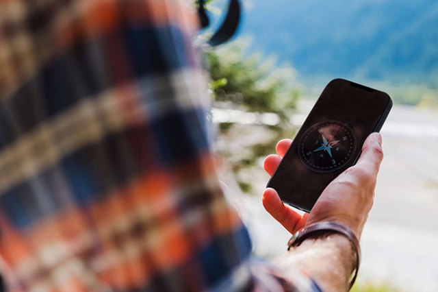 Man looking at phone that has a compass image