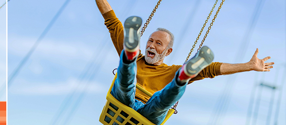 Man smiling with arms out on rusty amusement swing park ride