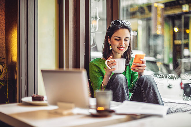 Woman on smart phone and laptop at cafe