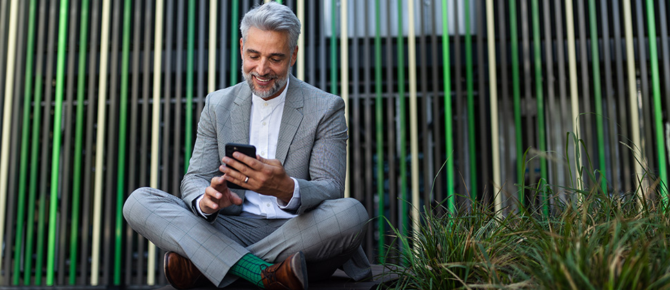 businessman sitting in park using smartphone